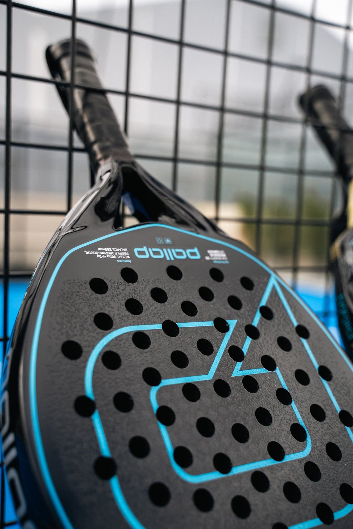 Pallap padel rackets resting against the court fence