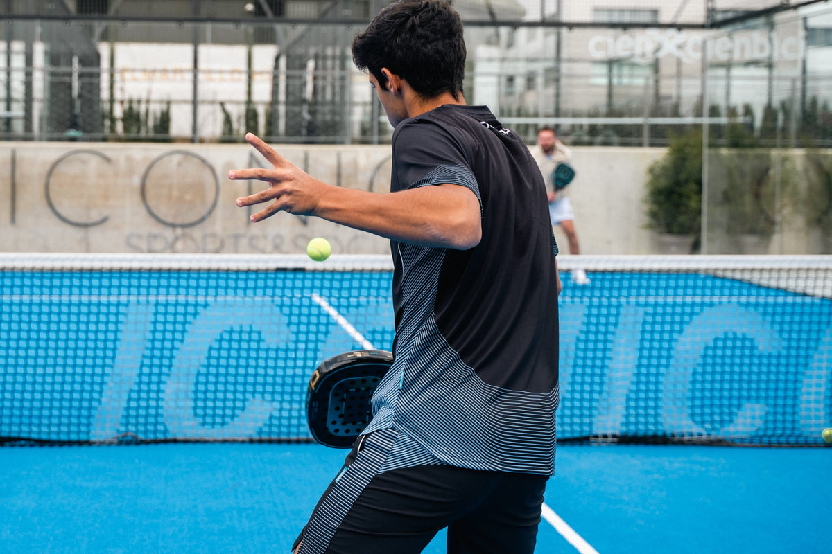 Padel player hitting a forehand with a Pallap racket on a blue court in Seville